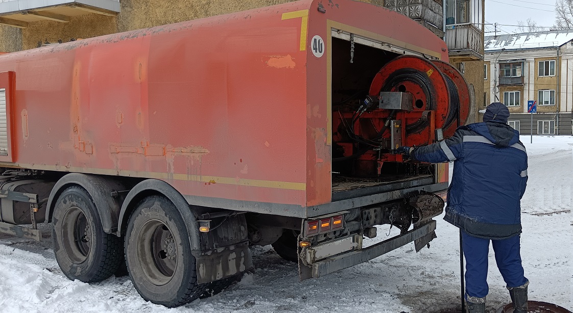 Каналопромывочная машина и работник прочищают засор в канализационной системе в Брянске
